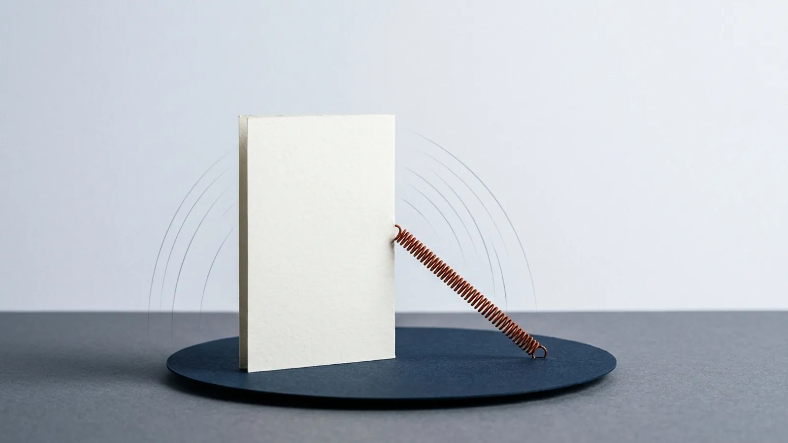 A sideways card is connected to its base by a stretched spring, pulling it back to its original orientation.