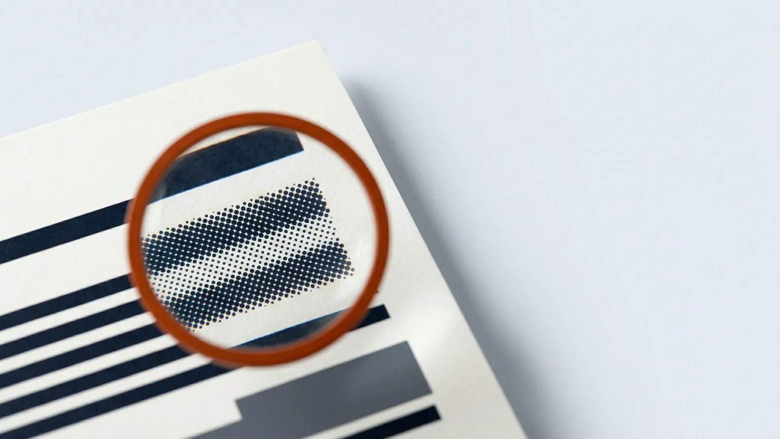 A magnifying glass reveals that printed text lines are actually made of coarse halftone dots.